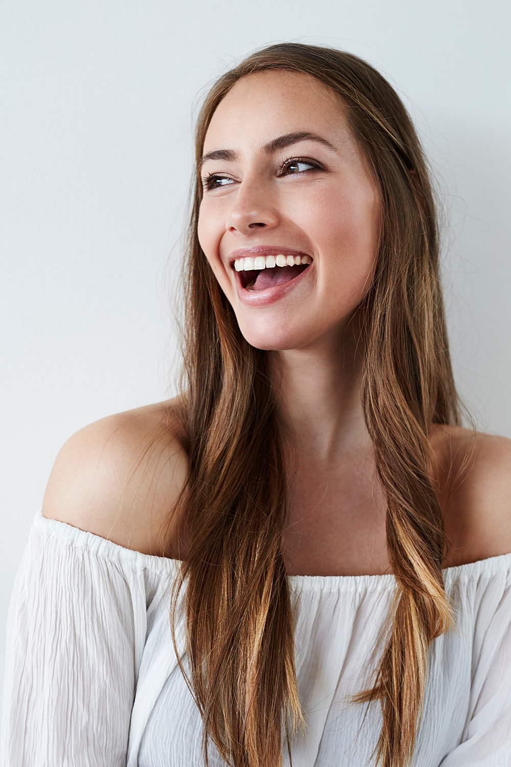 Smiling woman with long hair in white top.